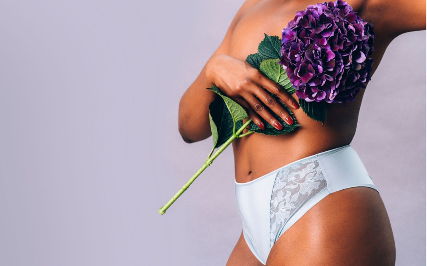 Woman holding purple flowers to cover breasts