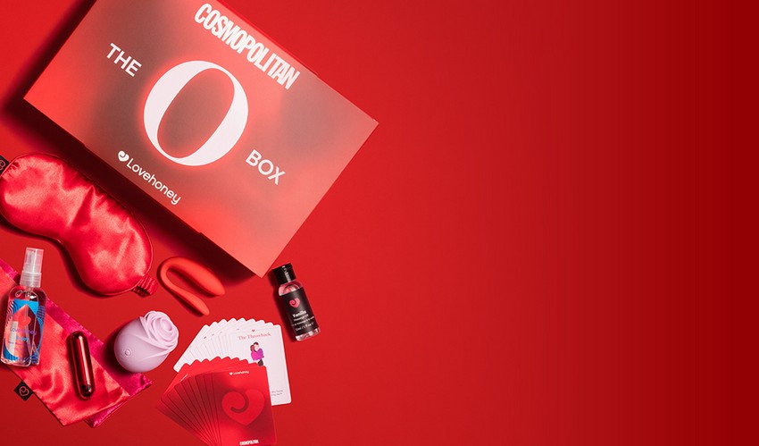 The Lovehoney x Cosmopolitan O Box showing sexual wellness products such as a pastel pink rose toy spilling onto a vibrant red background.
