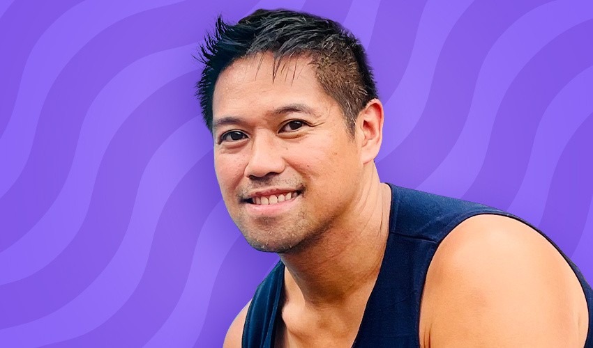 A photo of Gil Cruz in front of a purple swirl background.