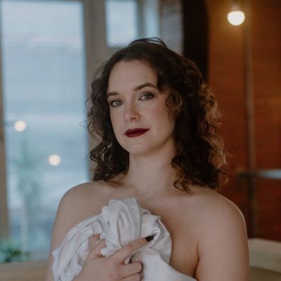 a woman with curly brown hair and red lipstick in a soft-lit room