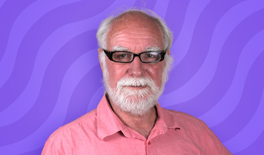 A photo of Keith Leach in front of a purple swirl background.