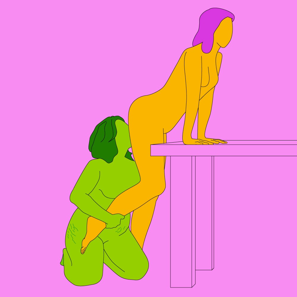 A naked illustrated couple in a rimming sex position. The giver is sat on the floor by the receiver's butt as they lean over a table.
