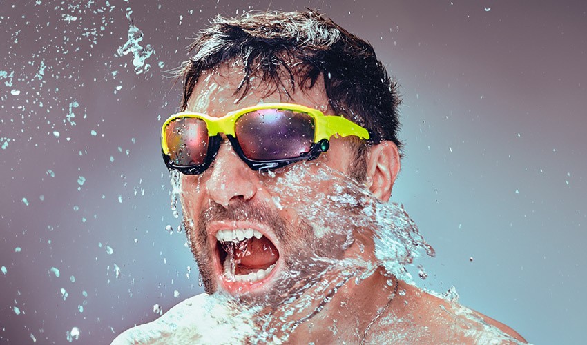 Henry, the co-founder of SULT, being splashed in the face with water while wearing reflective glasses